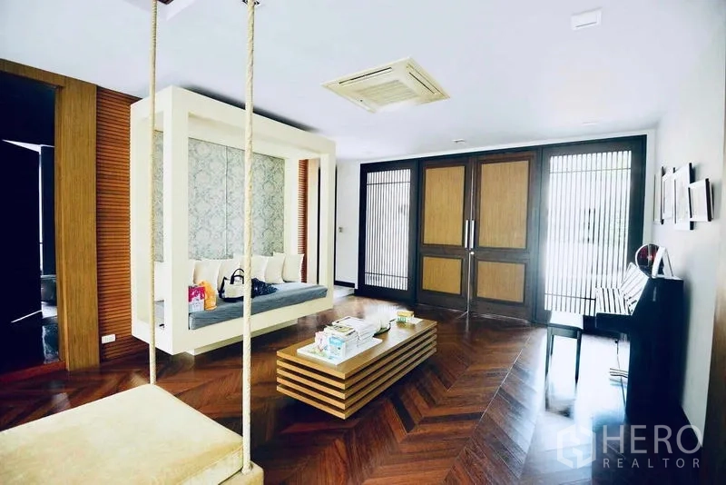 Detached House for sale in Bang Kapi, Bangkok - Lounge foyer with swing daybed, herringbone wood floor and wide double doors