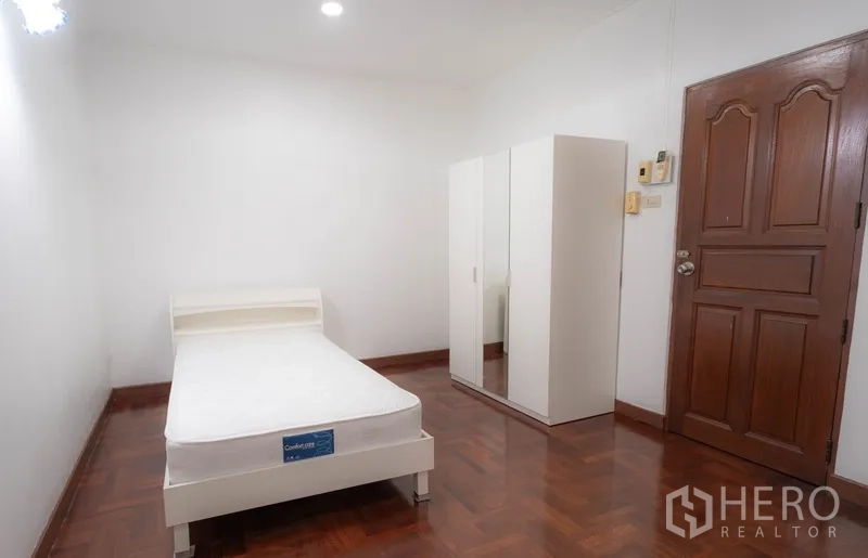 ทาวน์เฮาส์ ให้เช่าในWatthana, Bangkok - ห้องนอนเรียบง่าย เตียงเดี่ยว ตู้เสื้อสีขาว และประตูไม้