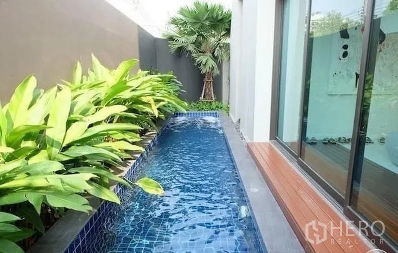 Townhouse for rent in Watthana, Bangkok - Narrow lap-style plunge pool with timber deck and tropical plants.