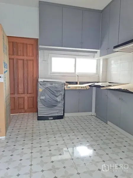 Detached House for rent in Prawet, Bangkok - Bright kitchen with grey cabinetry, patterned tile floor and a window above the sink.