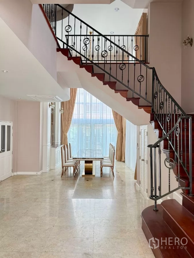 Townhouse for rent in Bang Kho Laem, Bangkok - Double-height foyer with staircase and dining area framed by floor-to-ceiling drapes