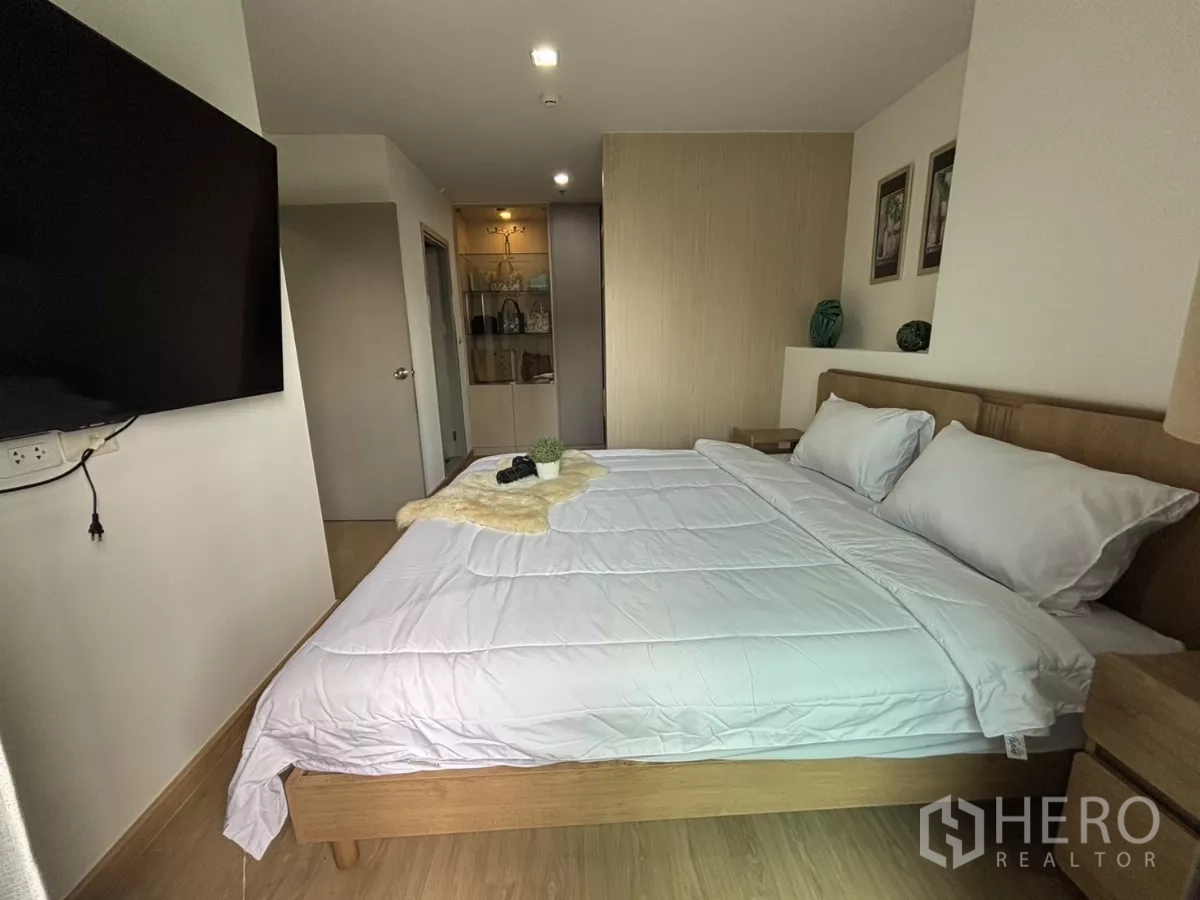 Condominium for rent in Phra Khanong, Bangkok - Bedroom with large TV, bedside tables and warm lighting.