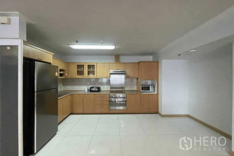 Condominium for rent in Watthana, Bangkok - Fitted kitchen with wood cabinetry, stainless oven, range hood and large refrigerator.