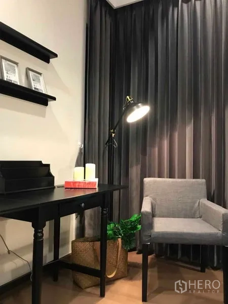 คอนโด ให้เช่าหรือขายในRatchathewi, Bangkok - มุมทำงานพร้อมโต๊ะสีดำ เก้าอี้มีพนักสีเทา ชั้นวางผนัง และผ้าม่านสูงจรดพื้น