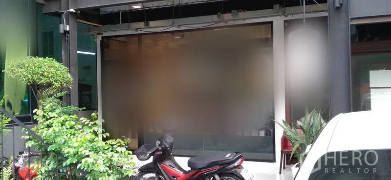 พื้นที่ขายปลีก ให้เช่าในWatthana, Bangkok - หน้าร้านกระจกฝ้า มีต้นไม้กระถางและที่จอดมอเตอร์ไซค์ด้านหน้า