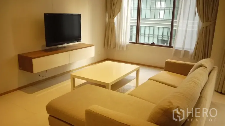 คอนโด ให้เช่าในKhlong Toei, Bangkok - ห้องนั่งเล่นสว่าง โซฟาแอลสีเบจ ทีวีติดผนัง โต๊ะกลาง และหน้าต่างบานใหญ่