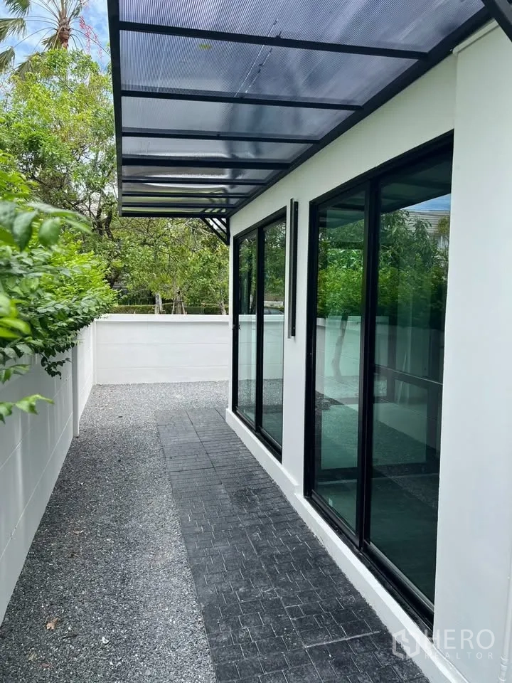 Townhouse for rent in Prawet, Bangkok - Covered side terrace with sliding glass doors and gravel path.