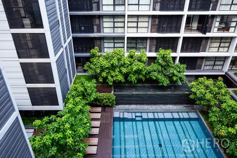 公寓 出租在Watthana, Bangkok - 中庭泳池被绿植与木栈道环绕，坐落于现代低层公寓内。