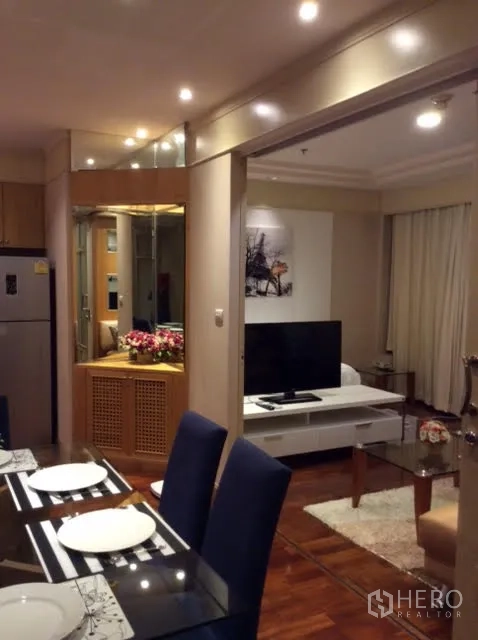 Condominium for rent in Pathum Wan, Bangkok - Open-plan living and dining with TV console, glass coffee table, and recessed lighting.