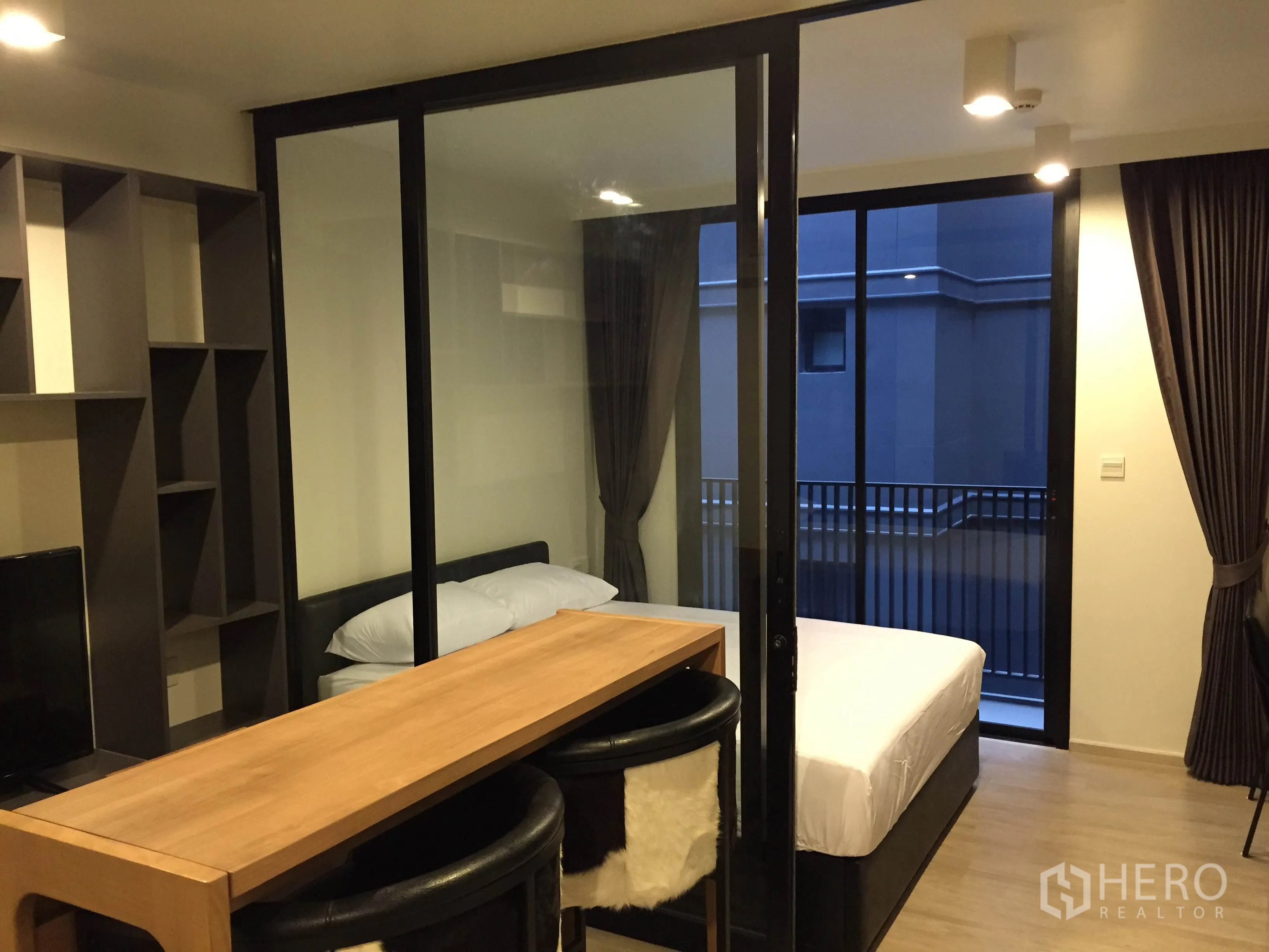 Condominium for rent in Pathum Wan, Bangkok - Compact one-bedroom layout with glass partition, bar-height dining table and balcony access.