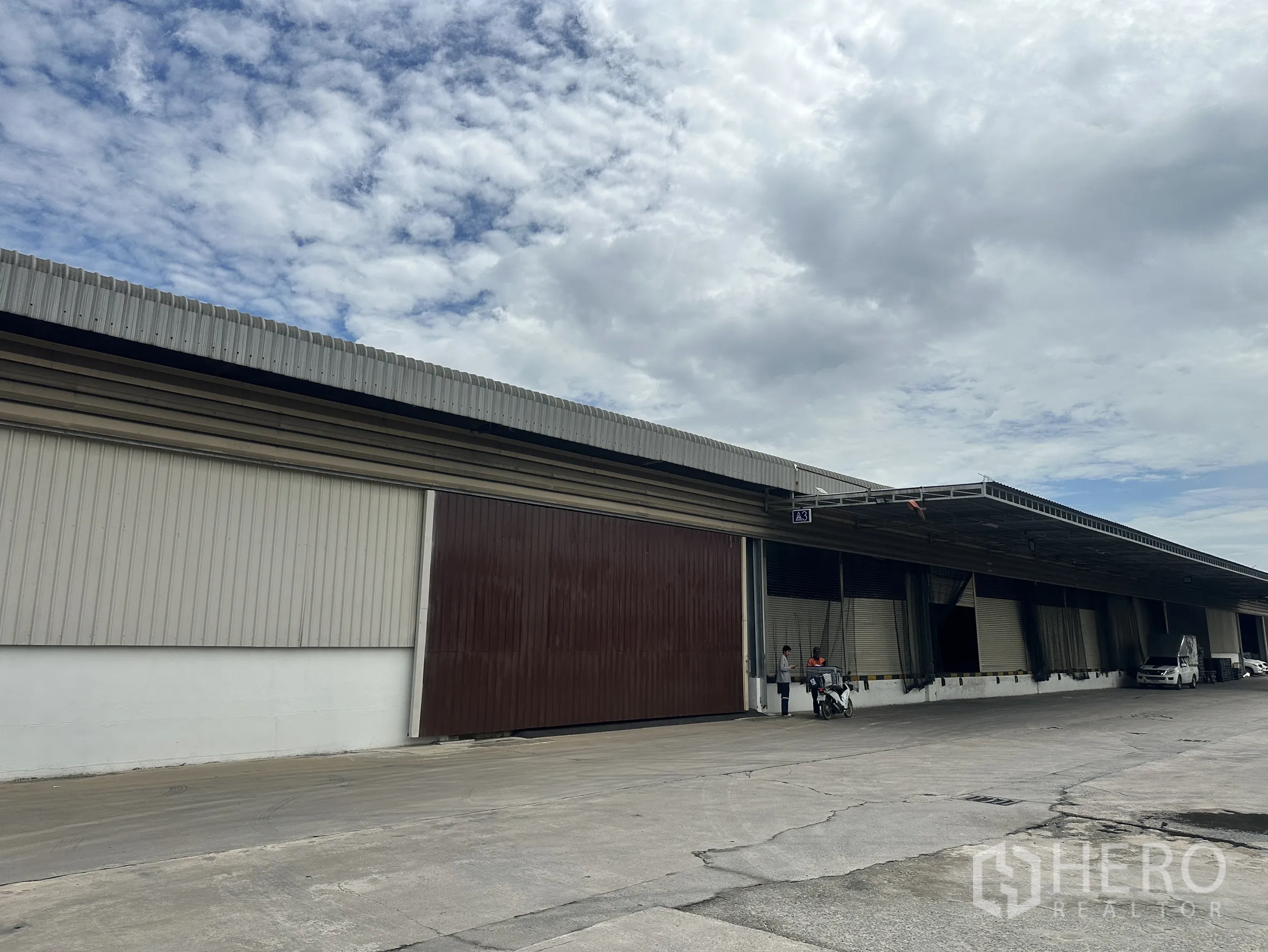 โรงงาน for rent in Lat Krabang, Bangkok - ด้านหน้าโกดังยาวต่อเนื่องพร้อมประตูม้วนหลายบานและทางรถบรรทุก