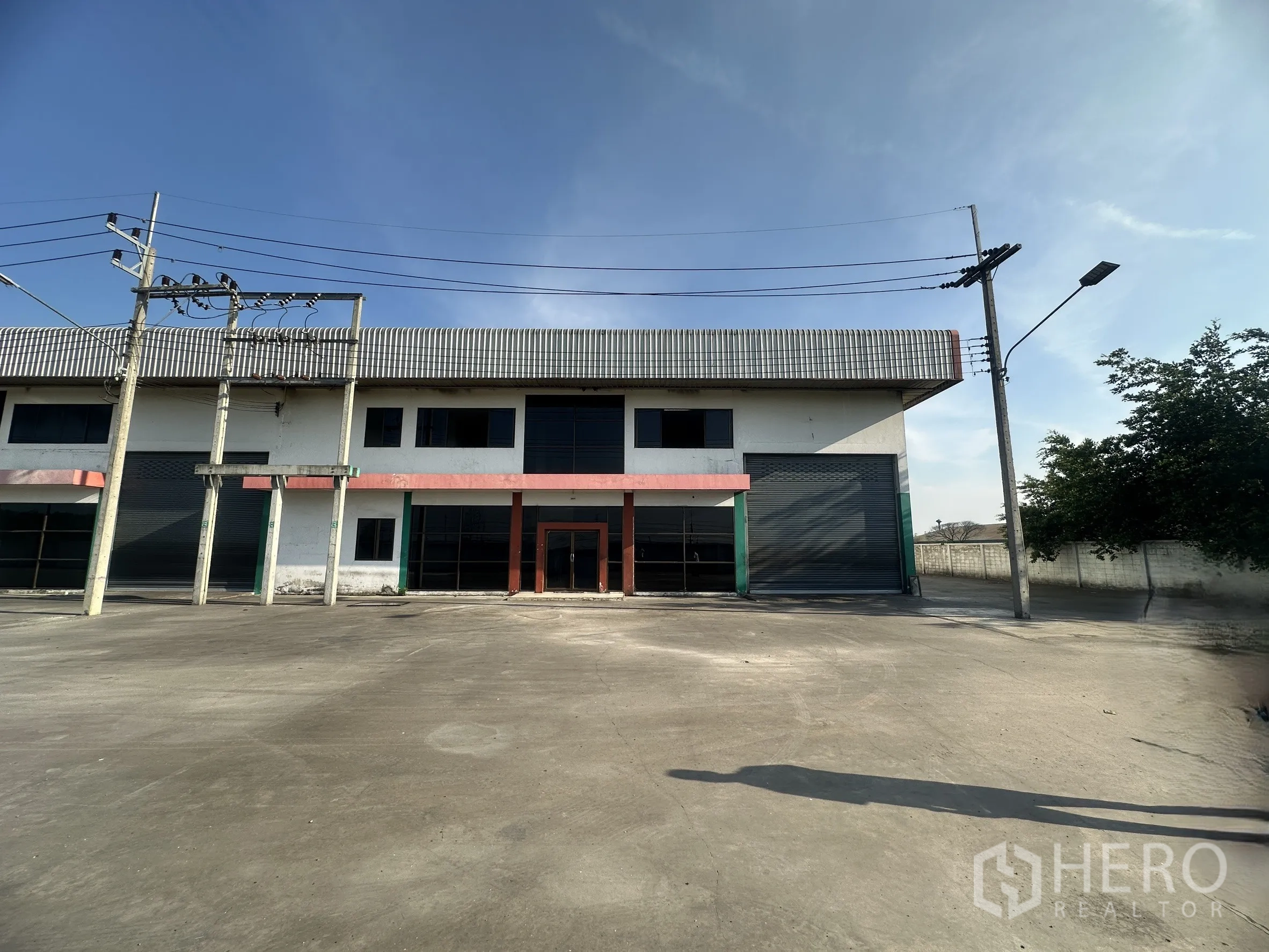 Factory for rent in Wang Noi, Phra Nakhon Si Ayutthaya - Front elevation of a factory unit with large roller shutters, glass entry, and parking apron.