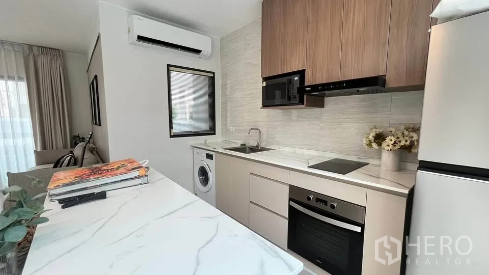 Townhouse for rent or sale in Bang Phli, Samut Prakan - Fitted kitchen with oven, cooktop, microwave, cabinets and refrigerator.