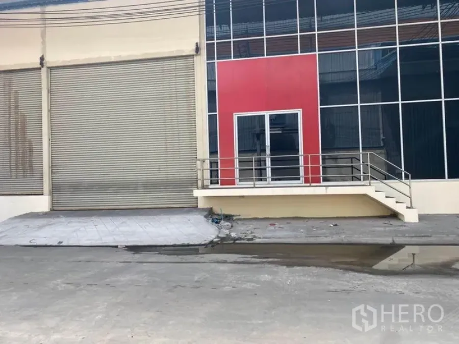 Factory for rent in Bang Phli, Samut Prakan - Factory frontage with large roller shutter, glass entry and red facade panel.