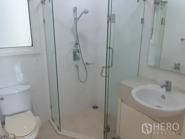 คอนโด ให้เช่าในKhlong Toei, Bangkok - ห้องน้ำโทนขาวพร้อมตู้กระจกอาบน้ำ อ่างล้างหน้า และโถสุขภัณฑ์ข้างหน้าต่าง