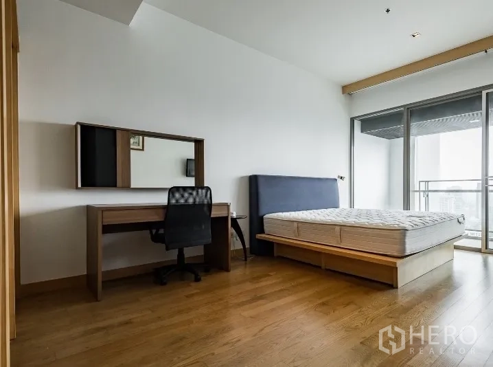 คอนโด ให้เช่าในWatthana, Bangkok - ห้องนอนหลักกว้าง เตียงยกพื้น โต๊ะทำงาน และทางออกสู่ระเบียงมองเห็นวิวสกายไลน์