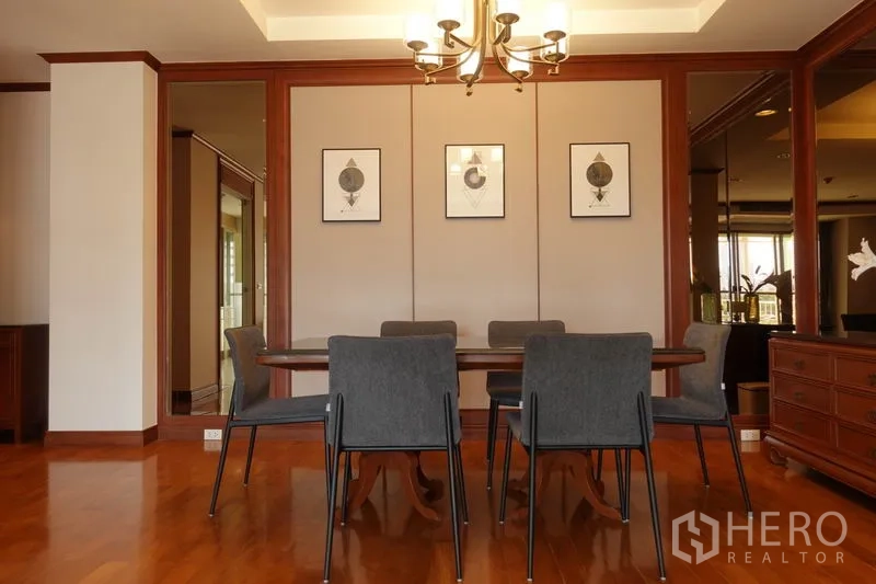 Condominium for rent in Khlong Toei, Bangkok - Dining area with chandelier, six chairs and warm wood paneling.
