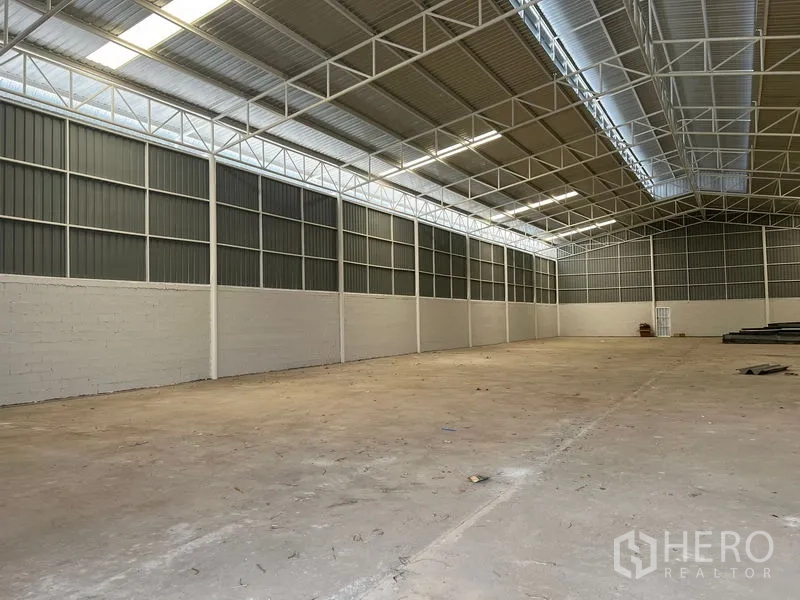 Warehouse for rent in Min Buri, Bangkok - Side view of warehouse showing ventilated metal panels and bright natural lighting.