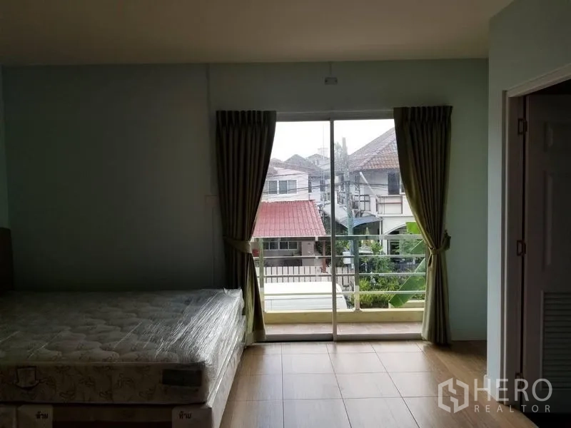 联排别墅 出租在Bang Kapi, Bangkok - 主卧连接阳台，推拉玻璃门俯瞰社区景观