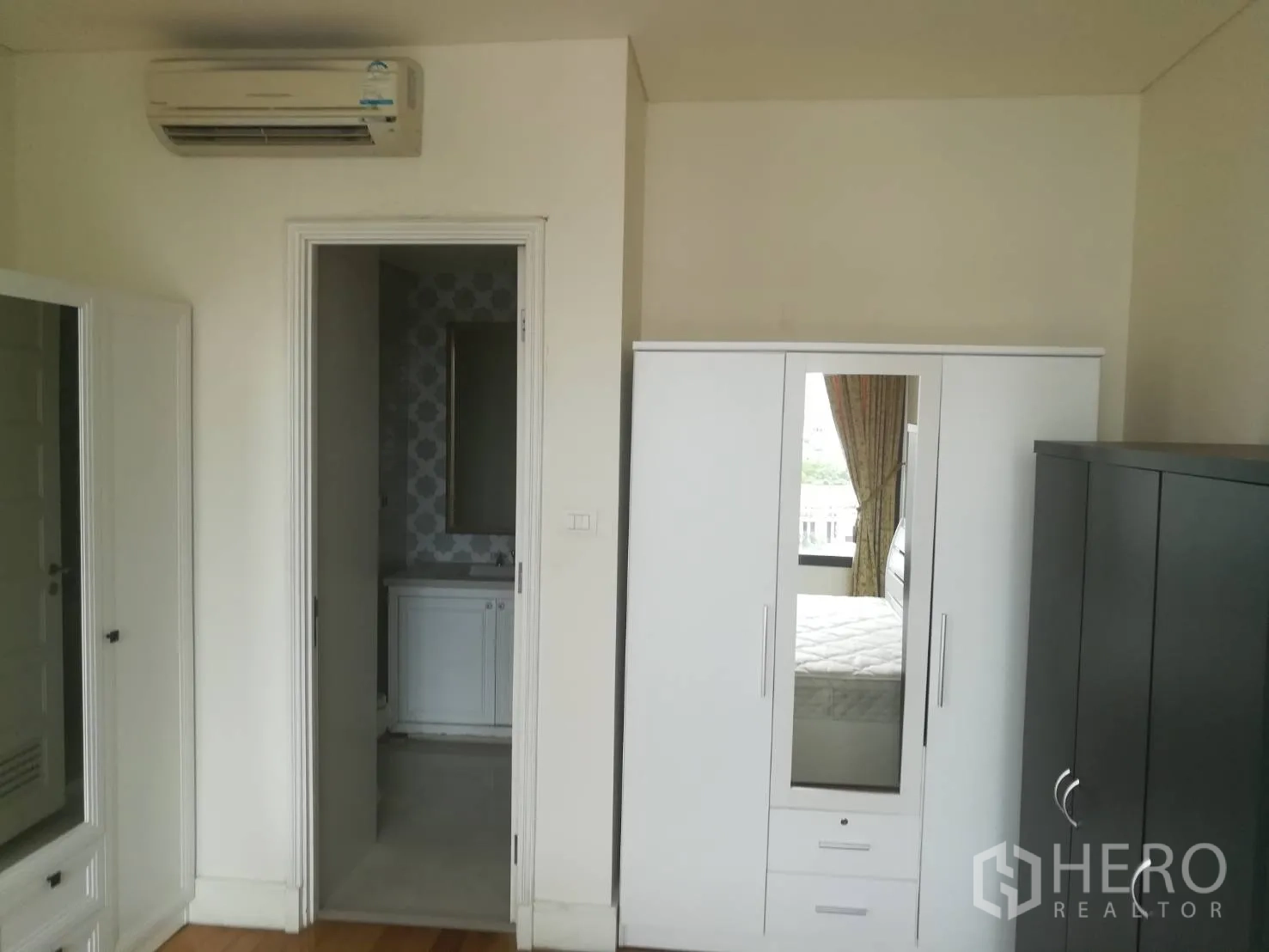 公寓 出售在Khlong Toei, Bangkok - 卧室一角，带镜衣柜、空调与通往浴室的门。