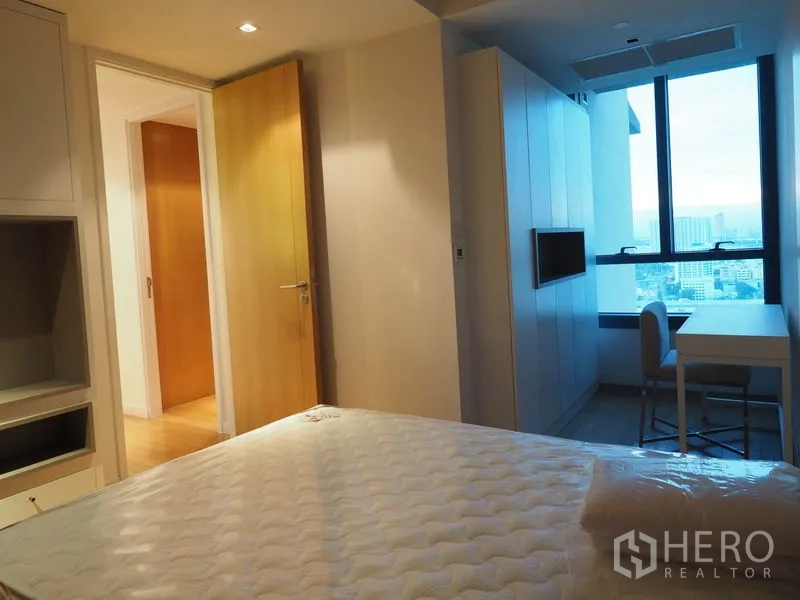 Condominium for rent in Yan Nawa, Bangkok - Second bedroom with desk by the window and custom cabinetry overlooking city skyline.