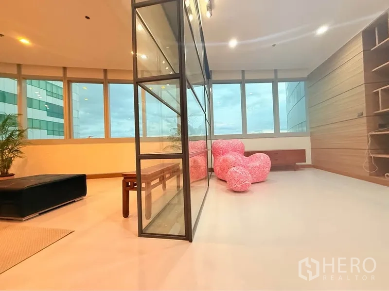 คอนโด ให้เช่าหรือขายในKhlong Toei, Bangkok - มุมห้องนั่งเล่น ผนังกั้นโลหะ-กระจก กระจกพาโนรามา และเก้าอี้ชมพู