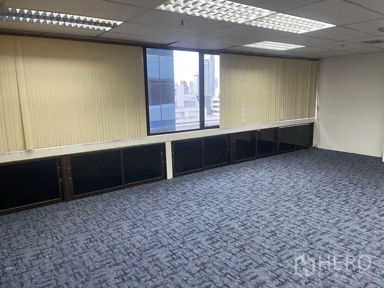 Office Space for rent in Khlong Toei, Bangkok - Bright office zone with a wide window and partial city view beside vertical blinds.