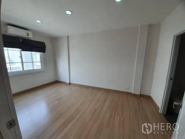 联排别墅 出租在Bang Na, Bangkok - 宽敞卧室，木纹地板、窗帘、空调，并可进入套内卫生间。