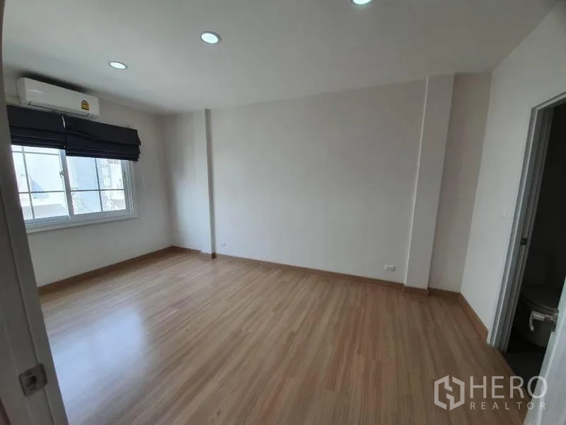 联排别墅 出租在Bang Na, Bangkok - 宽敞卧室，木纹地板、窗帘、空调，并可进入套内卫生间。