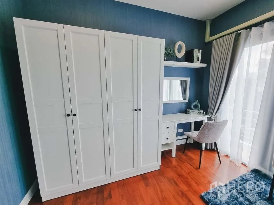 Detached House for rent or sale in Bang Phli, Samut Prakan - Compact room with white wardrobe, shelves, and vanity desk by a window.