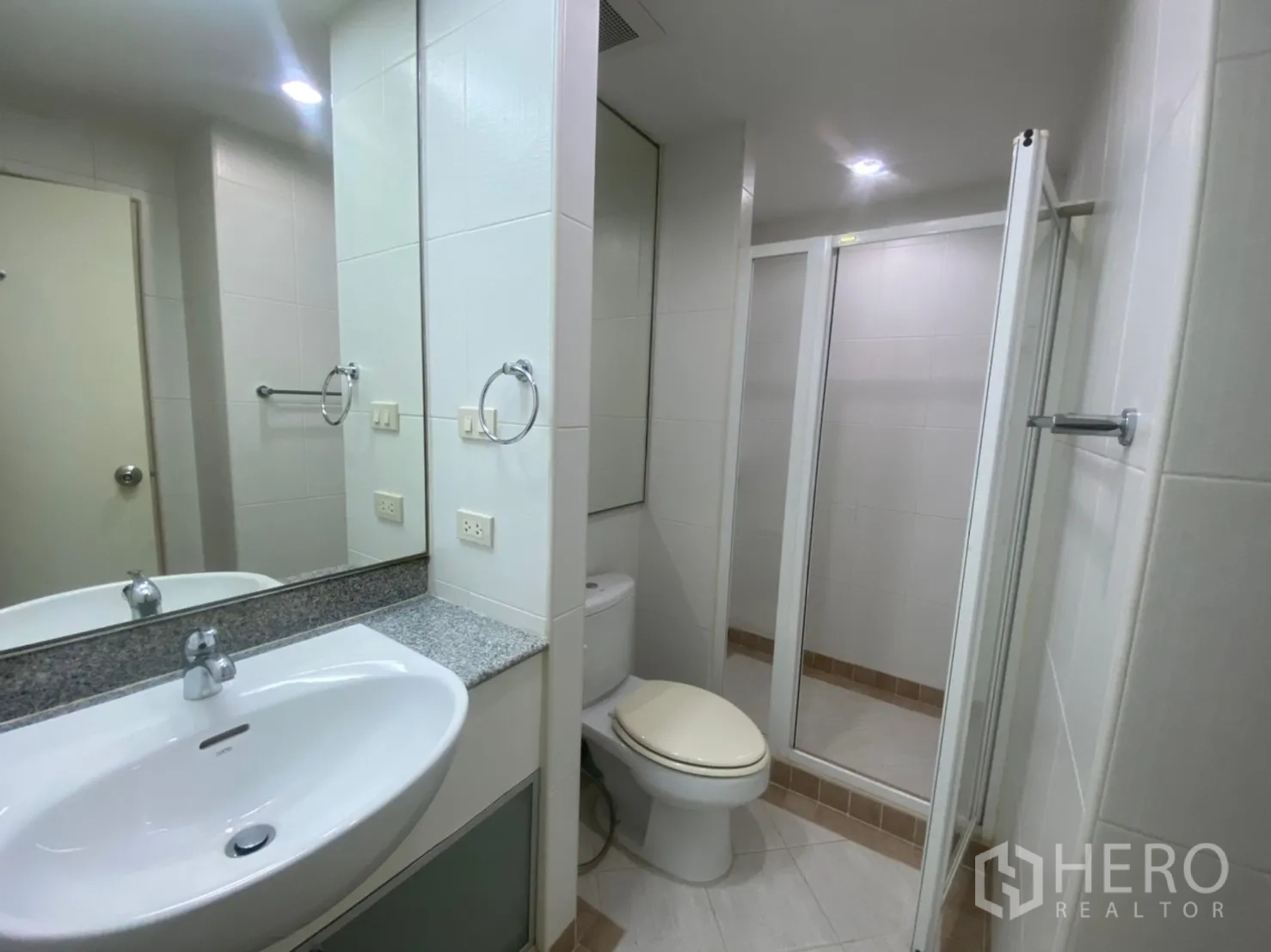Condominium for rent or sale in Sathon, Bangkok - Second bathroom with white tiles, vanity, toilet and shower cabin.