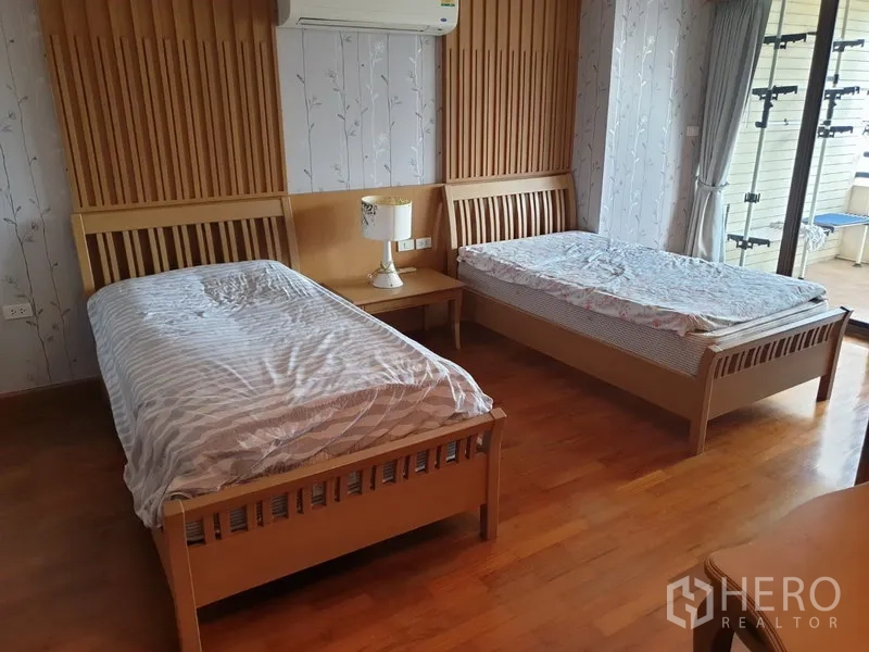 Condominium for rent in Watthana, Bangkok - Twin bedroom with two single beds and sliding glass doors opening to the balcony.