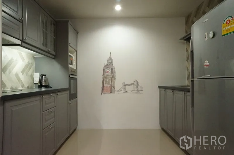 Condominium for rent in Watthana, Bangkok - Kitchen wall featuring Big Ben mural opposite a full-size refrigerator and cabinets.
