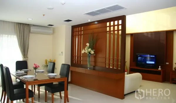 Apartment for rent in Khlong Toei, Bangkok - Open-plan dining area and living room divided by a decorative wooden feature wall