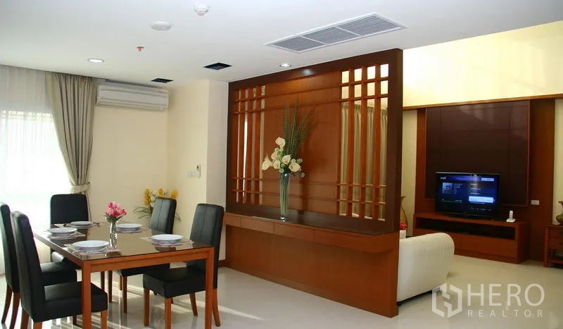 Apartment for rent in Khlong Toei, Bangkok - Open-plan dining area and living room divided by a decorative wooden feature wall