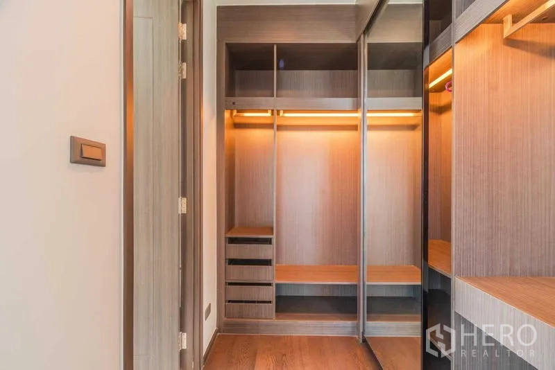 Condominium for rent or sale - Walk-in closet featuring illuminated wooden shelving and drawers.