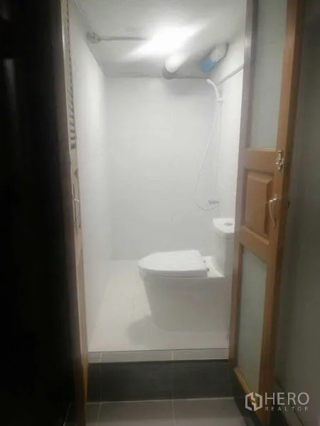 Shophouse for rent in Khlong Toei, Bangkok - Compact restroom with white walls, toilet, handheld bidet and shower.