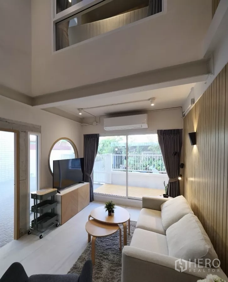 联排别墅 出租或出售在Watthana, Bangkok - 明亮客厅角度，落地玻璃门通向前平台。