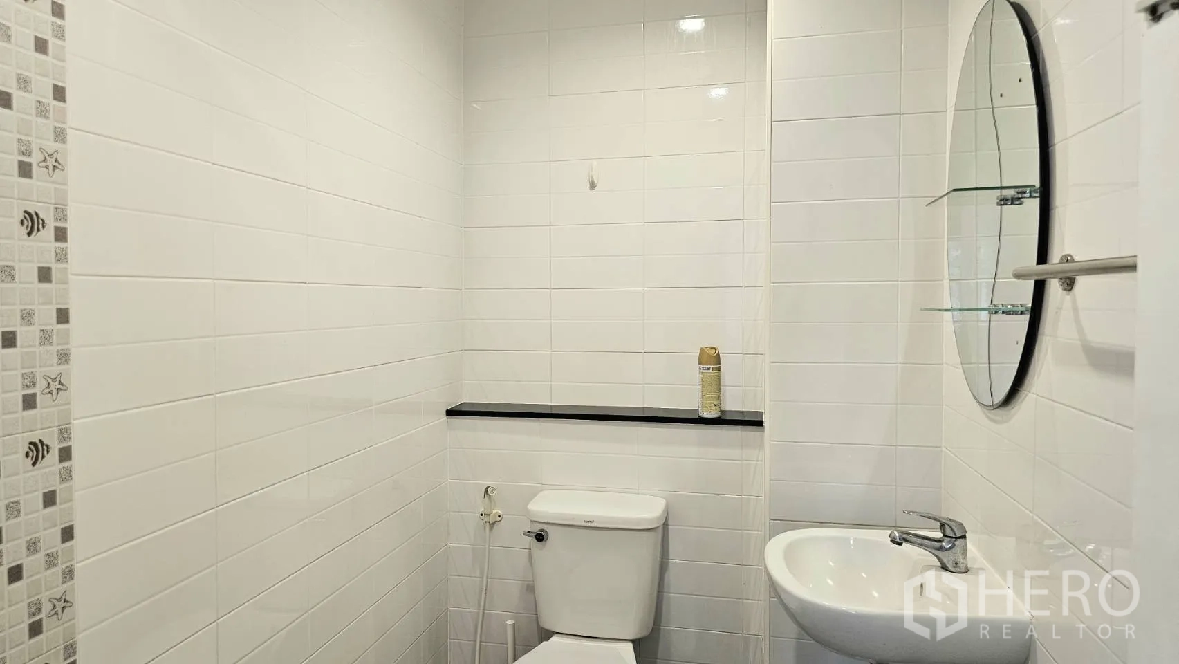 Detached House for rent in Saphan Sung, Bangkok - Guest bathroom with white tiles, toilet, sink, mirror, and shelf.