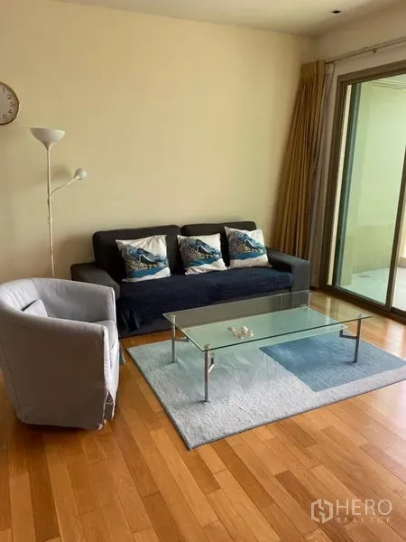 公寓 出租在Khlong Toei, Bangkok - 舒适客厅，沙发与单椅，玻璃茶几，推拉门通向阳台。