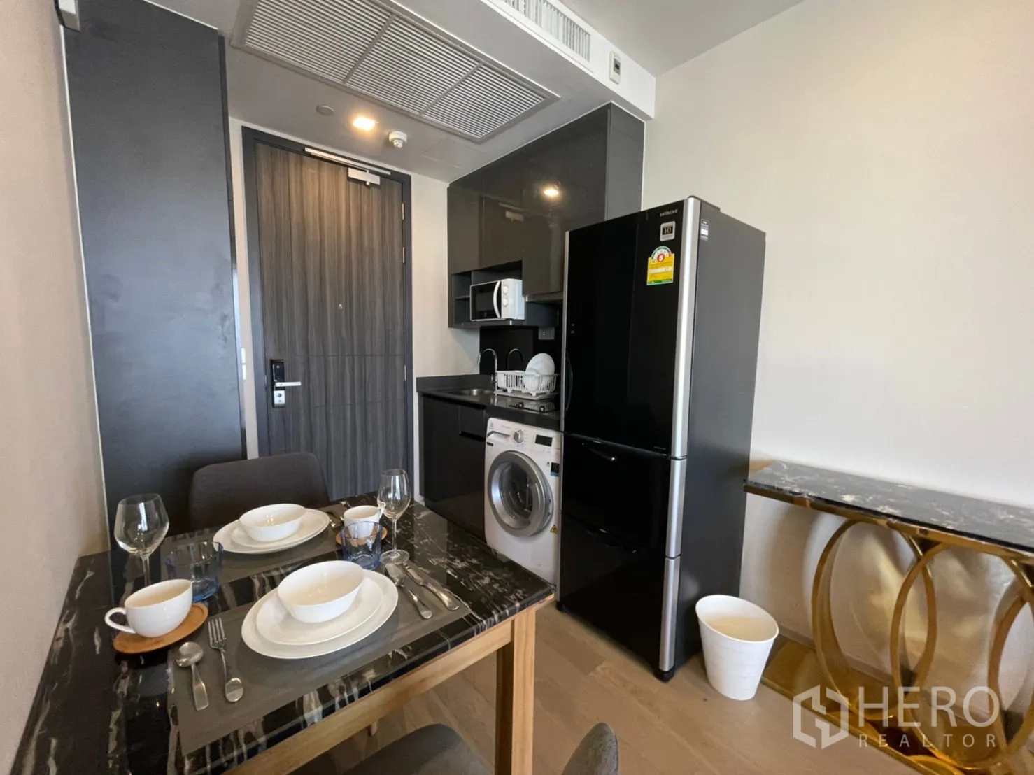 公寓 for rent in Watthana, Bangkok - 紧凑厨房配黑色冰箱、微波炉、洗衣机与餐桌。