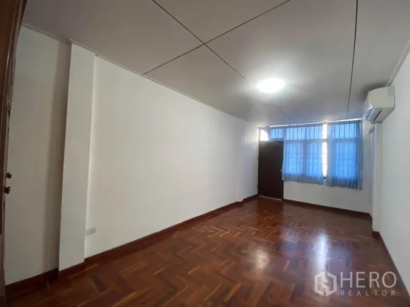 ทาวน์เฮาส์ ให้เช่าในWatthana, Bangkok - ห้องนอนพร้อมเครื่องปรับอากาศ ม่านสีน้ำเงิน และพื้นไม้.