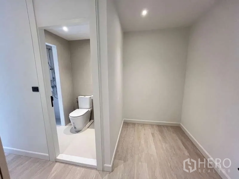 Townhouse for sale in Khlong Toei, Bangkok - Small corridor with doorway to a minimalist bathroom in neutral tones.