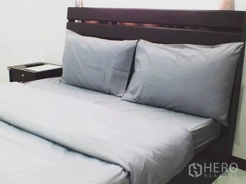 Shophouse for sale in Lam Luk Ka, Pathum Thani - Bedroom with double bed, gray bedding and wooden headboard.