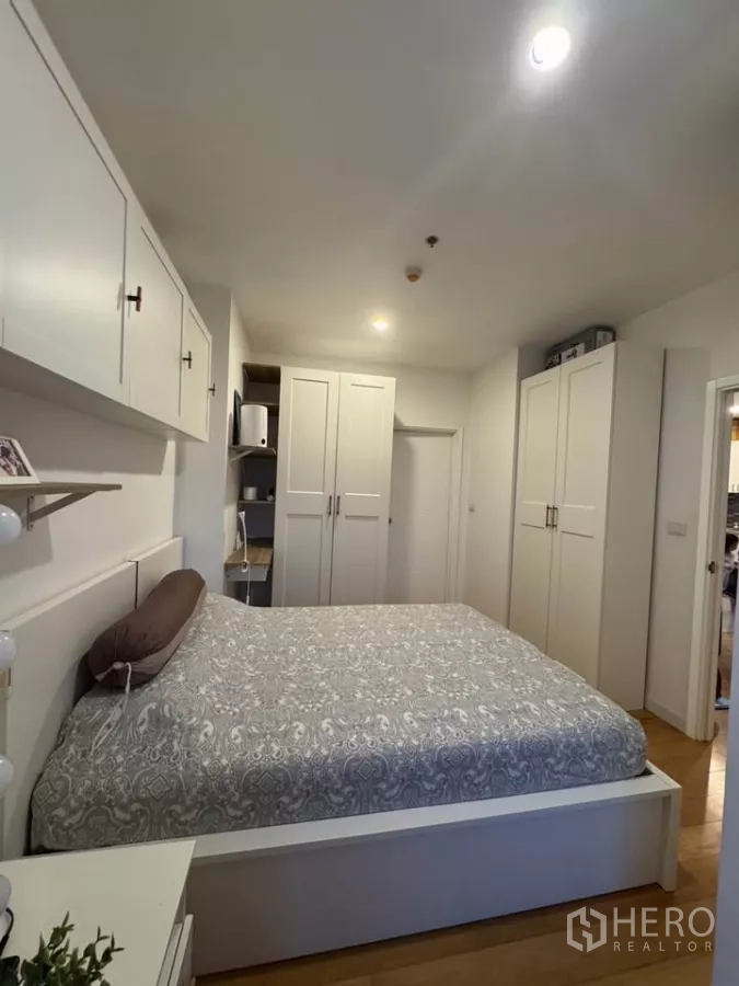 Condominium for rent in Watthana, Bangkok - Primary bedroom with multiple wardrobes and dressing area on wood floors.