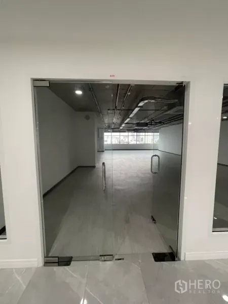 办公空间 出租在Bang Rak, Bangkok - 玻璃双开门通向明亮的开放式办公区，灰色地面与整面窗户。