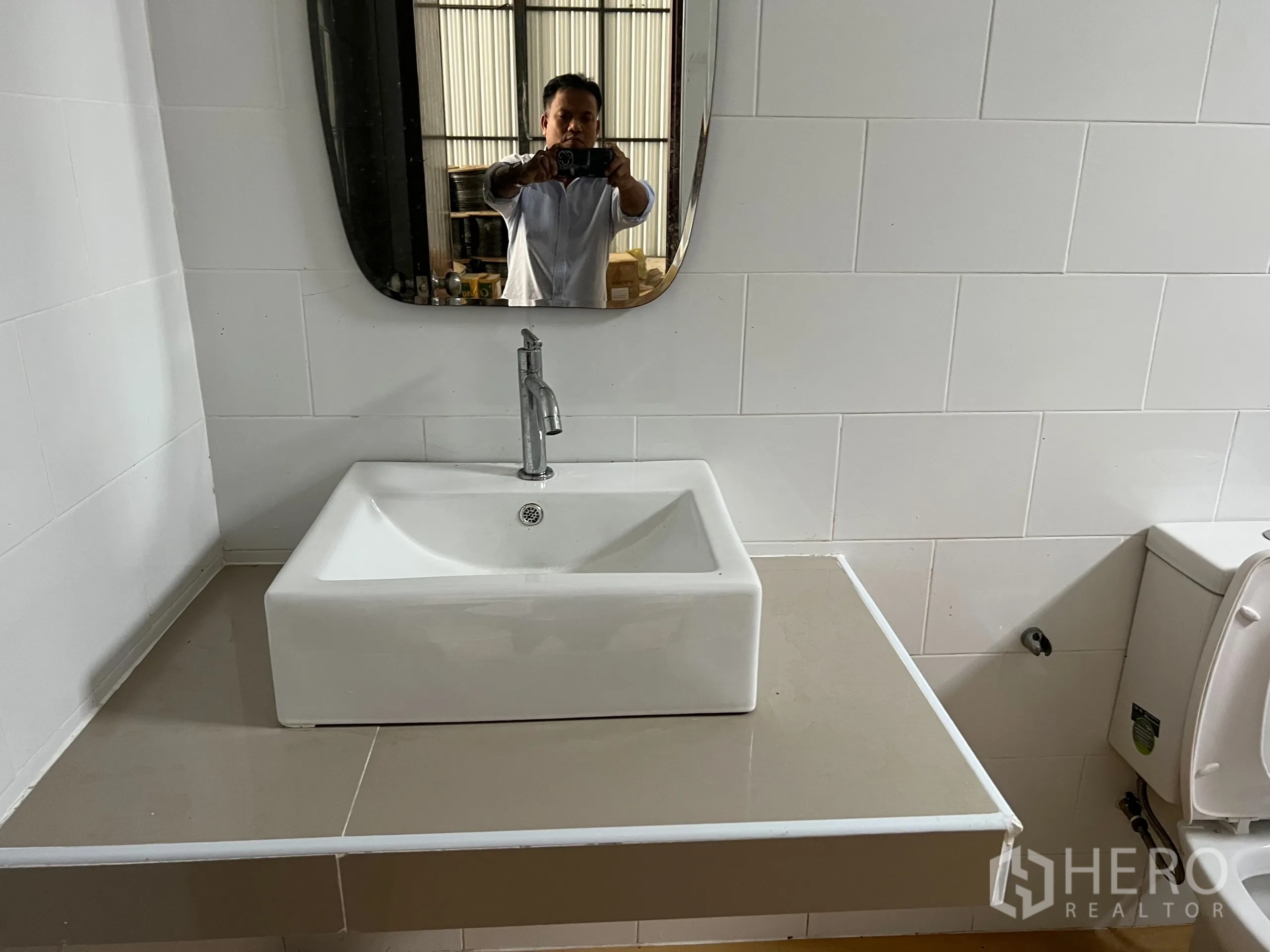 Warehouse for sale in Bang Len, Nakhon Pathom - Close-up of modern square basin and mirror in a white-tiled bathroom.