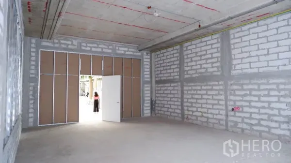 พื้นที่ขายปลีก ให้เช่าในKhlong Toei, Bangkok - ภายในพื้นที่ค้าปลีกโล่ง แสดงทางเข้ากว้างและผนังบล็อกพร้อมตกแต่ง.