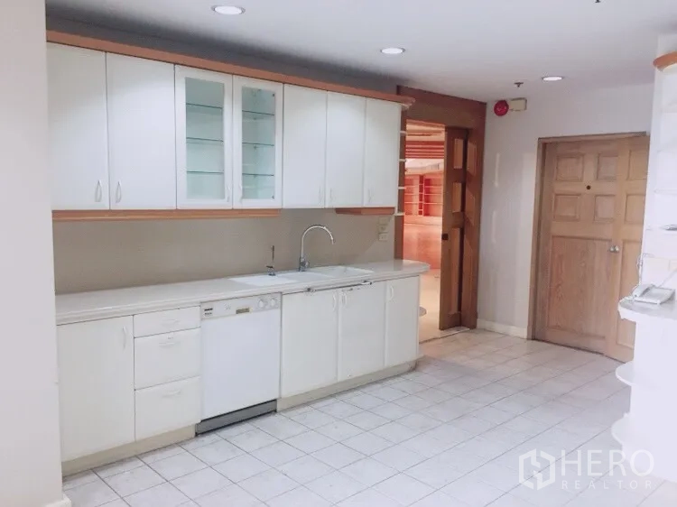 Condominium for rent in Watthana, Bangkok - White fitted kitchen with upper cabinets, sink and dishwasher on tiled floor.