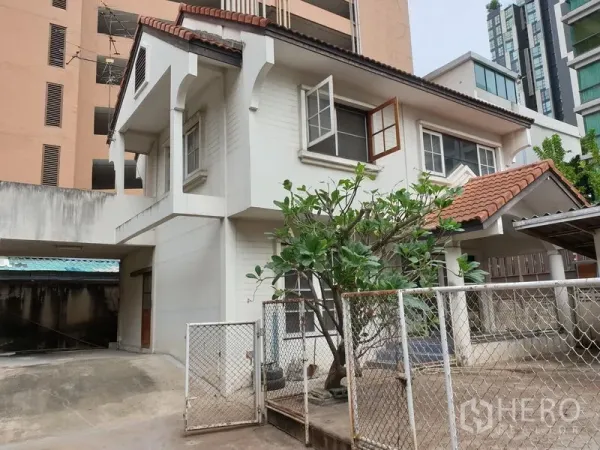 独立式住宅 出租或出售在Watthana, Bangkok - 两层独栋住宅，红瓦屋顶，带大门与车棚，前院有成树。